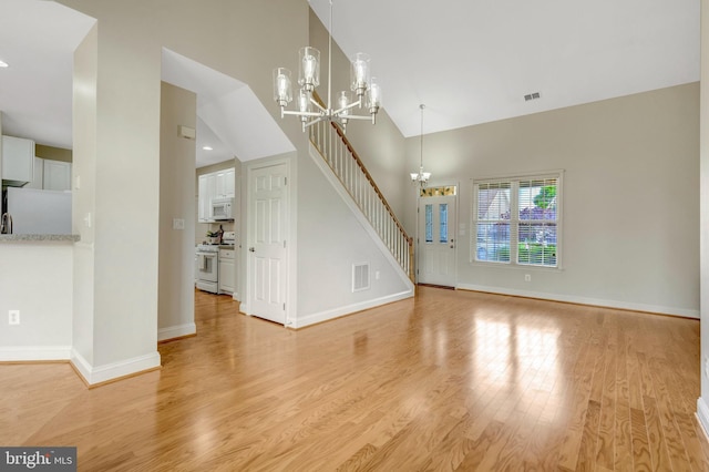 13854 Cinch Ln, Gainesville, VA 20155 - unfurnished living room featuring a chandelier, high vaulted ceiling, light wood-style floors, and stairs