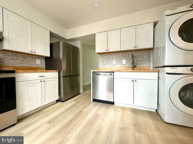 7851 W Point Ct, Manassas, VA 20109 - kitchen with appliances with stainless steel finishes, stacked washing machine and dryer, light wood-style flooring, and tasteful backsplash