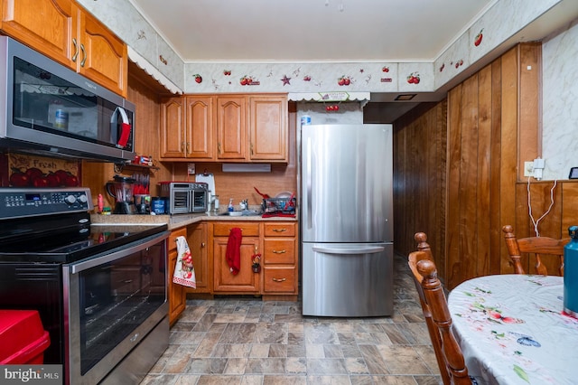 930 Elm St, Reading, PA 19601 - kitchen featuring stainless steel appliances, stone finish flooring, brown cabinetry, and light countertops