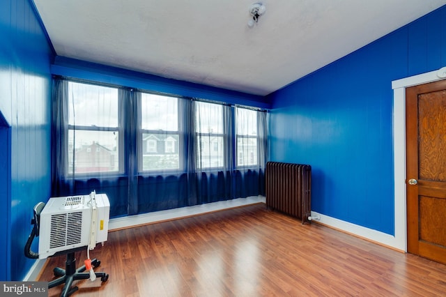 930 Elm St, Reading, PA 19601 - empty room with radiator, vaulted ceiling, wood finished floors, and a wall mounted AC