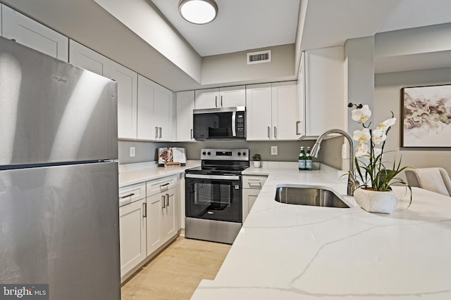 2400 Clarendon Blvd Unit 811, Arlington, VA 22201 - kitchen featuring appliances with stainless steel finishes, white cabinetry, light wood finished floors, and light stone counters