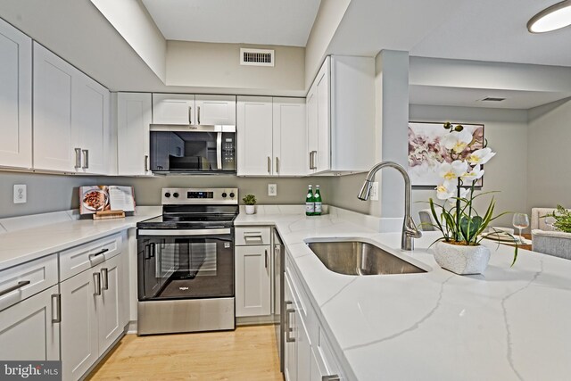 2400 Clarendon Blvd Unit 811, Arlington, VA 22201 - kitchen featuring stainless steel appliances, white cabinets, light stone counters, and light wood finished floors