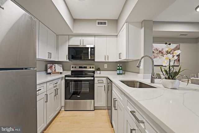 2400 Clarendon Blvd Unit 811, Arlington, VA 22201 - kitchen featuring stainless steel appliances, white cabinets, light stone countertops, and light wood-style flooring