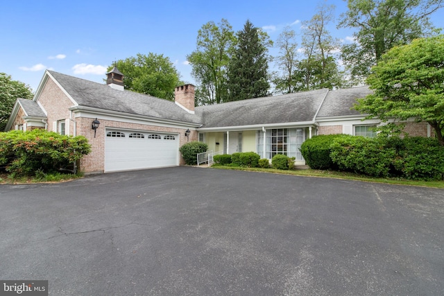 418 1st Ave, Clearfield, PA 16830 - view of front of home with an attached garage, asphalt driveway, brick siding, a chimney, and roof with shingles