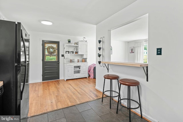 7918 Wicker Ln, La Plata, MD 20646 - kitchen featuring freestanding refrigerator, a kitchen bar, and tile patterned floors