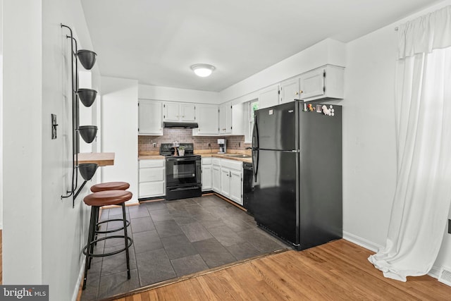 7918 Wicker Ln, La Plata, MD 20646 - kitchen with black appliances, under cabinet range hood, light countertops, backsplash, and white cabinetry