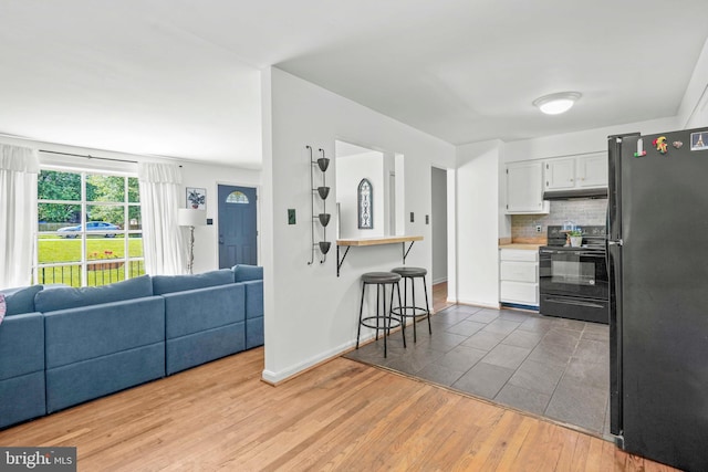 7918 Wicker Ln, La Plata, MD 20646 - kitchen featuring black appliances, open floor plan, under cabinet range hood, and wood finished floors