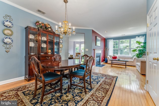 17 Paddock Ln, Flemington, NJ 08822 - dining space with light wood-type flooring, a chandelier, ornamental molding, and a fireplace with flush hearth