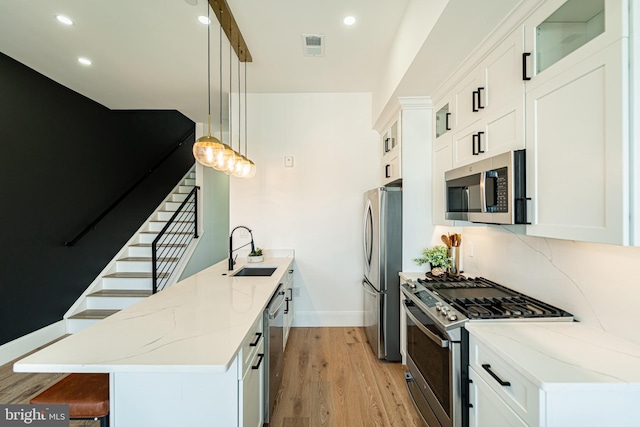 2517 Ontario Rd NW Unit Ph7, Washington, DC 20009 - kitchen featuring appliances with stainless steel finishes, a peninsula, light wood-type flooring, glass insert cabinets, and a kitchen breakfast bar