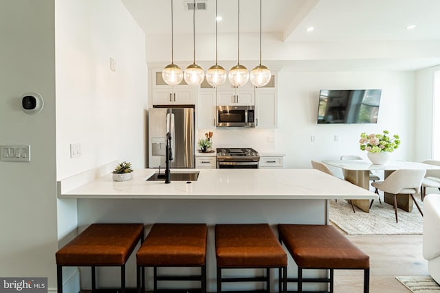 2517 Ontario Rd NW Unit Ph7, Washington, DC 20009 - kitchen featuring appliances with stainless steel finishes, a breakfast bar, a peninsula, decorative light fixtures, and light countertops