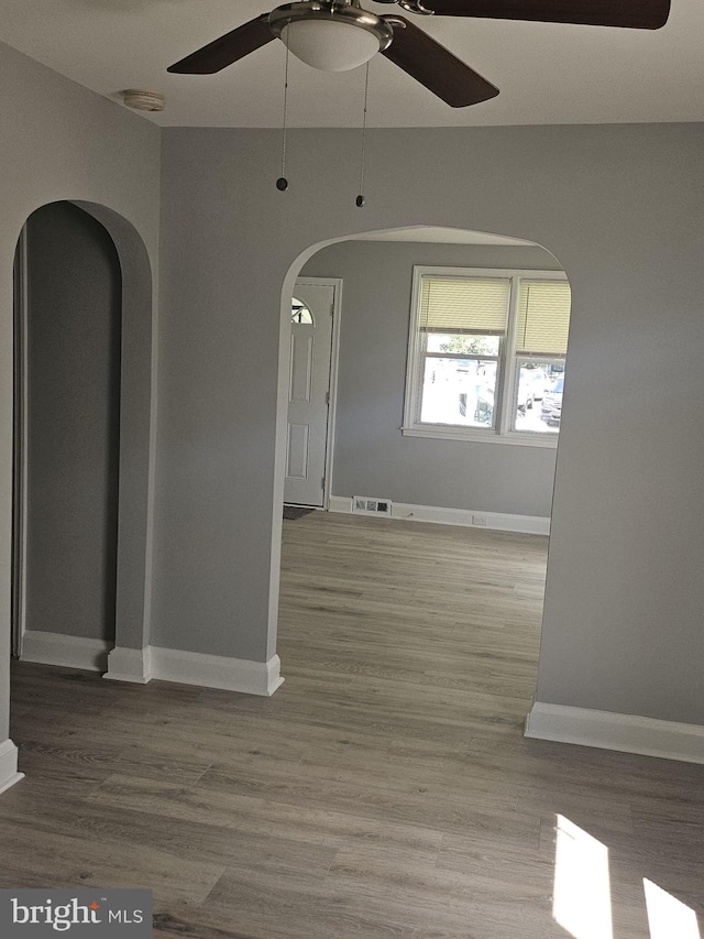 1608 Howard, Baltimore, MD 21221 - empty room featuring ceiling fan, arched walkways, and wood finished floors