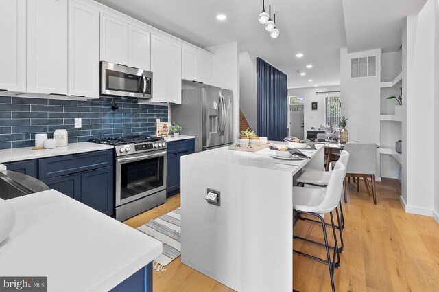 3306 E Lombard St, Baltimore, MD 21224 - kitchen with appliances with stainless steel finishes, blue cabinets, a kitchen island, a breakfast bar, and recessed lighting