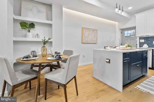 3306 E Lombard St, Baltimore, MD 21224 - kitchen featuring light wood-style floors, white cabinets, light countertops, a kitchen island, and tasteful backsplash