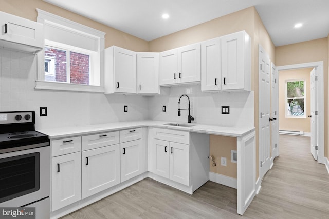 2839 N 9th St, Philadelphia, PA 19133 - kitchen featuring stainless steel electric stove, light wood finished floors, tasteful backsplash, white cabinetry, and a baseboard radiator
