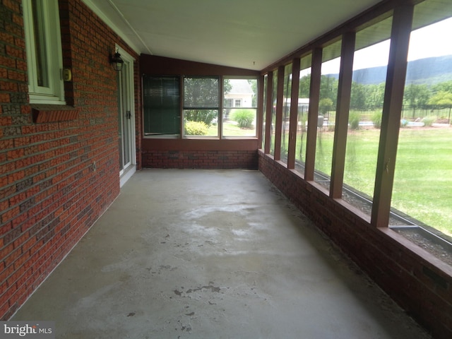 109 Ridgeview Dr, Lewistown, PA 17044 - unfurnished sunroom featuring brick wall, unfinished concrete flooring, and lofted ceiling