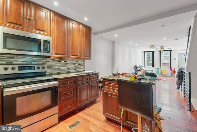 1847 Gerritt St, Philadelphia, PA 19146 - kitchen with appliances with stainless steel finishes, light wood-style flooring, decorative backsplash, recessed lighting, and dark stone countertops