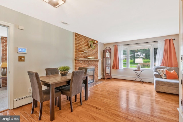29 Cedar Dr, Sterling, VA 20164 - dining area featuring baseboard heating, light wood finished floors, and a brick fireplace