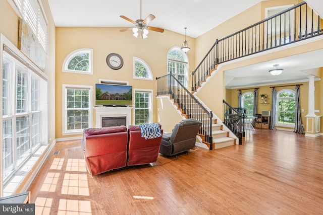 1340 Mountain View Rd, Stafford, VA 22554 - living area featuring a glass covered fireplace, wood finished floors, stairs, a towering ceiling, and a ceiling fan
