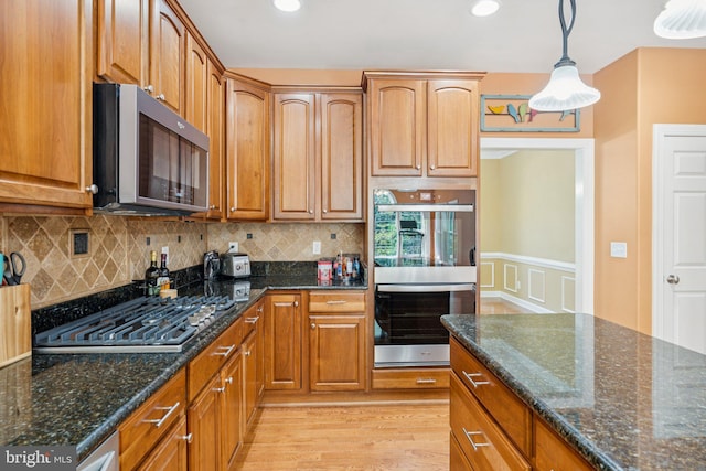 1340 Mountain View Rd, Stafford, VA 22554 - kitchen with appliances with stainless steel finishes, light wood-type flooring, decorative backsplash, dark stone countertops, and decorative light fixtures
