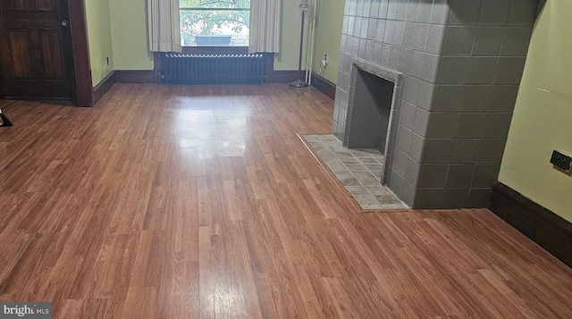 1032 N 4th St, Reading, PA 19601 - unfurnished living room featuring radiator, wood finished floors, and a tiled fireplace