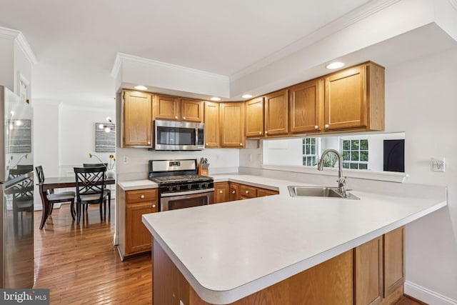 2640 E Colonial Dr, Upper Chichester, PA 19061 - kitchen featuring appliances with stainless steel finishes, crown molding, a peninsula, light countertops, and wood finished floors