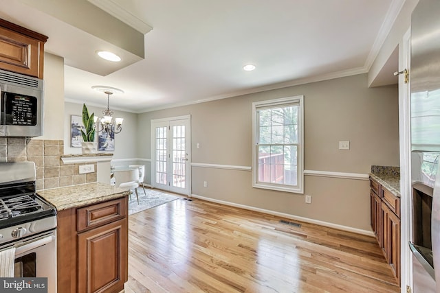 9009 Marie Ct, Lorton, VA 22079 - kitchen featuring stainless steel appliances, brown cabinets, healthy amount of natural light, light wood-style floors, and crown molding