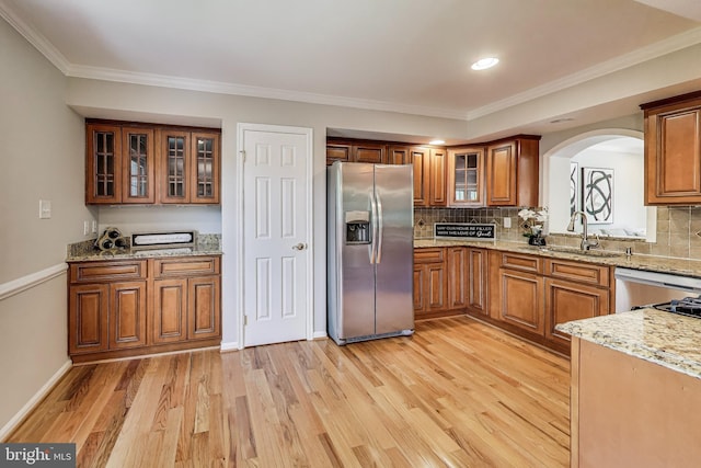 9009 Marie Ct, Lorton, VA 22079 - kitchen featuring appliances with stainless steel finishes, brown cabinets, arched walkways, light wood-style flooring, and crown molding