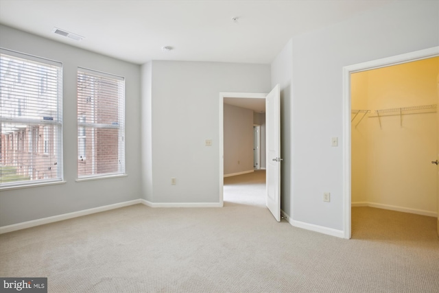 2655 Prosperity Ave Unit 100, Fairfax, VA 22031 - unfurnished bedroom featuring light colored carpet, multiple windows, a spacious closet, and a closet