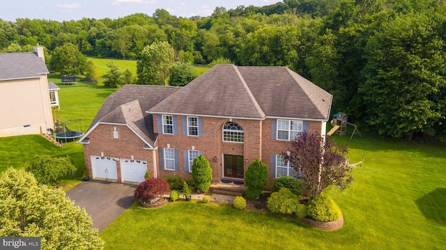14 Stanley Dr, Monroe Township, NJ 08831 - colonial home featuring driveway, a front yard, a trampoline, and a wooded view