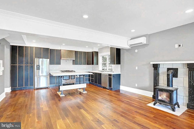 127 Spruce St, Middletown, PA 17057 - kitchen featuring appliances with stainless steel finishes, an AC wall unit, wall chimney range hood, light countertops, and decorative backsplash