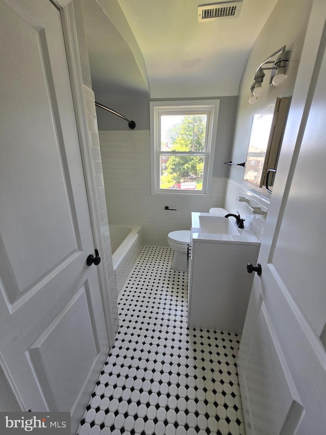 940 E 41st St, Baltimore, MD 21218 - full bathroom featuring vanity, tile patterned flooring, tile walls, lofted ceiling, and bathtub / shower combination