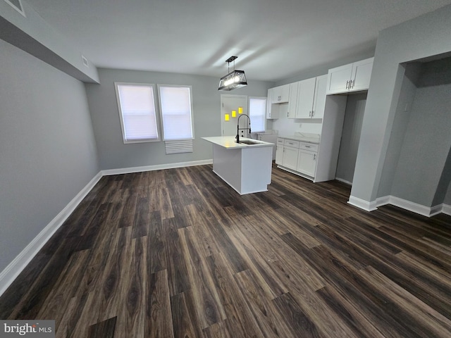 940 E 41st St, Baltimore, MD 21218 - kitchen featuring dark wood-style flooring, an island with sink, white cabinets, light countertops, and hanging light fixtures