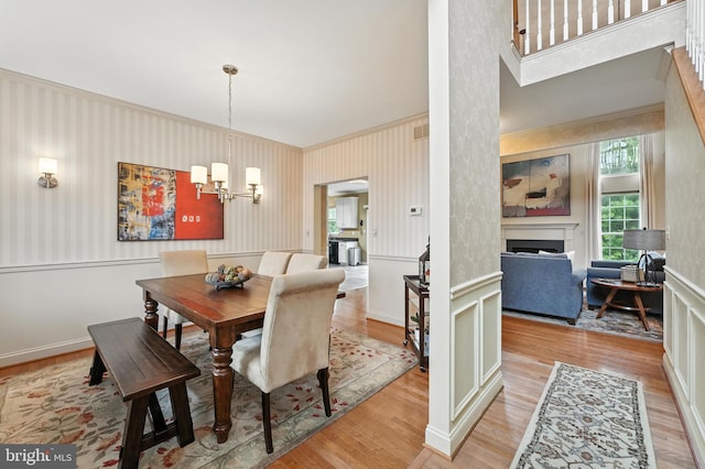 28 White Birch Blvd, Bear, DE 19701 - dining space with light wood-style flooring, a chandelier, a wainscoted wall, a fireplace, and ornamental molding