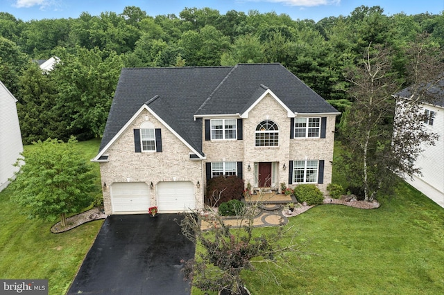 28 White Birch Blvd, Bear, DE 19701 - colonial house featuring asphalt driveway, an attached garage, roof with shingles, a front yard, and a wooded view