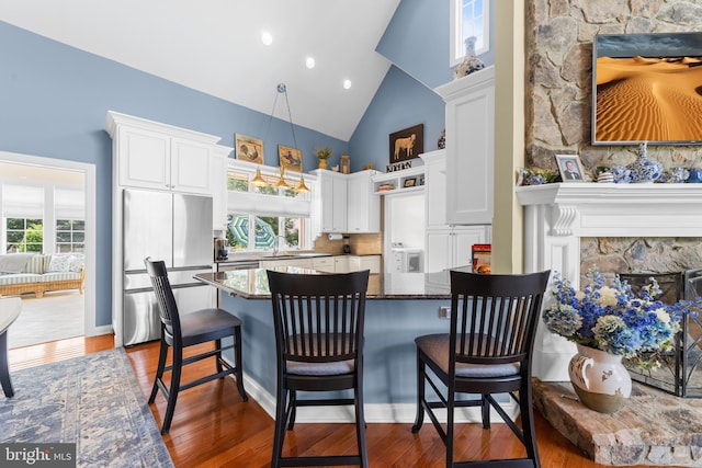 336 Lincoln Rd, Pilesgrove, NJ 08098 - kitchen with stainless steel fridge, high vaulted ceiling, white cabinets, a high end fireplace, and dark wood-style flooring