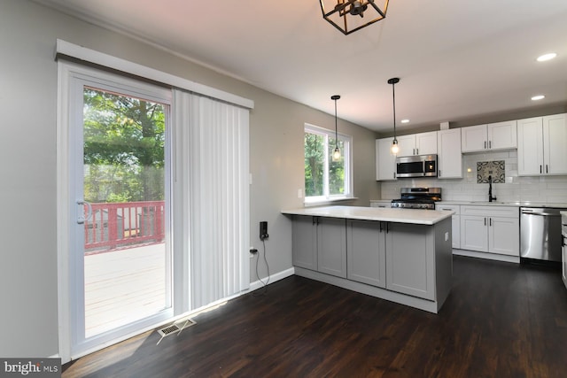 754 Second St, Woodbury Heights, NJ 08097 - kitchen featuring appliances with stainless steel finishes, dark wood finished floors, a peninsula, light countertops, and decorative backsplash