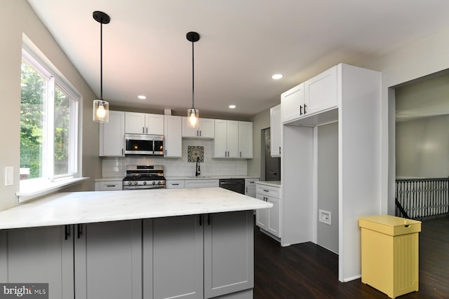 754 Second St, Woodbury Heights, NJ 08097 - kitchen featuring stainless steel appliances, a peninsula, dark wood-type flooring, decorative backsplash, and light stone counters