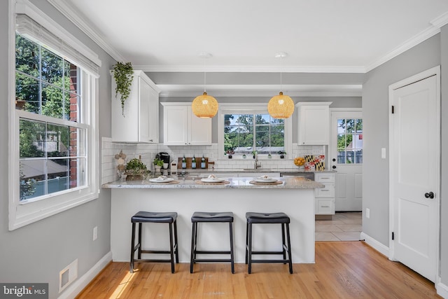 1305 Heather Hill Rd, Baltimore, MD 21239 - kitchen with white cabinetry, tasteful backsplash, a peninsula, a breakfast bar area, and light stone counters