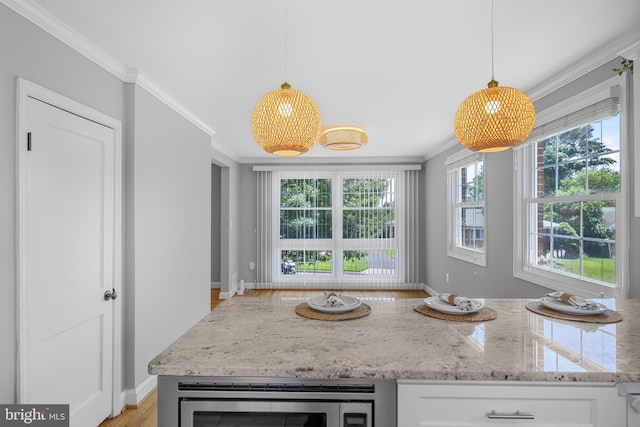1305 Heather Hill Rd, Baltimore, MD 21239 - kitchen featuring stainless steel microwave, ornamental molding, healthy amount of natural light, light stone countertops, and white cabinets