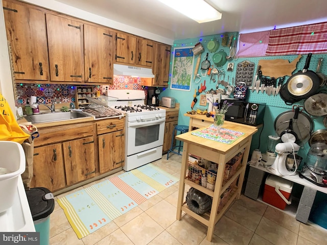316-322 W Wildey St, Philadelphia, PA 19123 - kitchen featuring white range with gas stovetop, under cabinet range hood, black microwave, brown cabinets, and light tile patterned floors