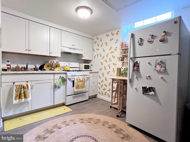 316-322 W Wildey St, Philadelphia, PA 19123 - kitchen with white appliances, under cabinet range hood, light wood-style floors, white cabinetry, and wallpapered walls