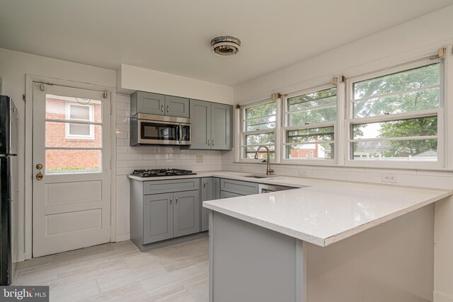1916 Porter Ave, Suitland, MD 20746 - kitchen featuring stainless steel microwave, gray cabinets, gas stovetop, a peninsula, and light stone counters