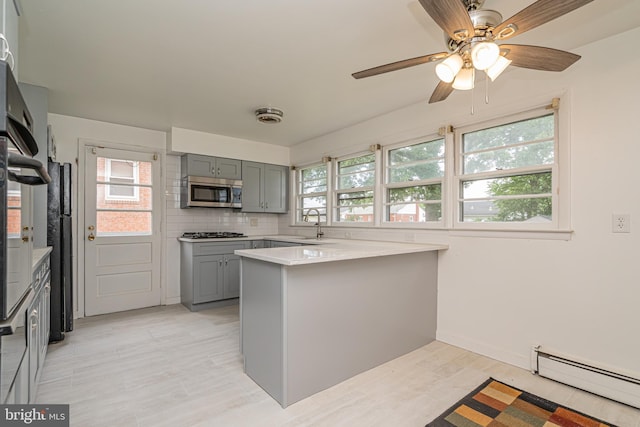 1916 Porter Ave, Suitland, MD 20746 - kitchen with stainless steel microwave, baseboard heating, gray cabinetry, gas cooktop, and a peninsula