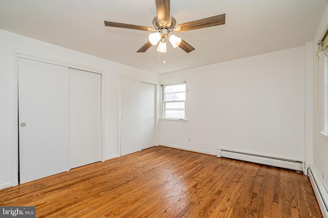 1916 Porter Ave, Suitland, MD 20746 - unfurnished bedroom featuring a baseboard radiator, two closets, wood finished floors, and a ceiling fan