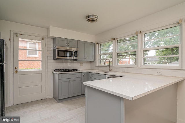 1916 Porter Ave, Suitland, MD 20746 - kitchen with gray cabinets, stainless steel microwave, gas stovetop, a peninsula, and backsplash