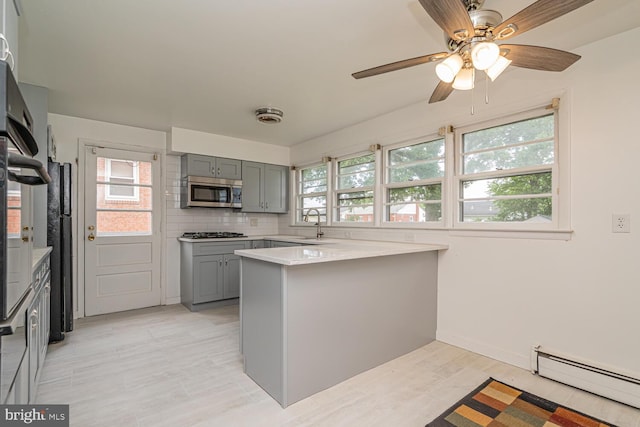 1916 Porter Ave, Suitland, MD 20746 - kitchen featuring stainless steel microwave, a baseboard heating unit, gray cabinetry, a peninsula, and gas stovetop