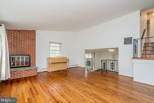 1916 Porter Ave, Suitland, MD 20746 - unfurnished living room featuring wood finished floors, a baseboard heating unit, a fireplace, and a baseboard radiator