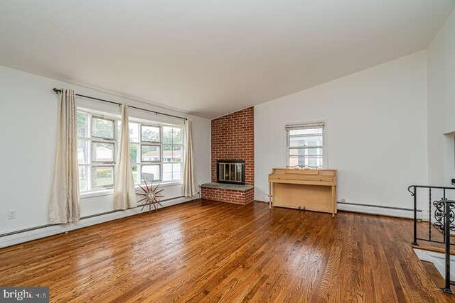 1916 Porter Ave, Suitland, MD 20746 - unfurnished living room with lofted ceiling, wood finished floors, healthy amount of natural light, a baseboard radiator, and a fireplace