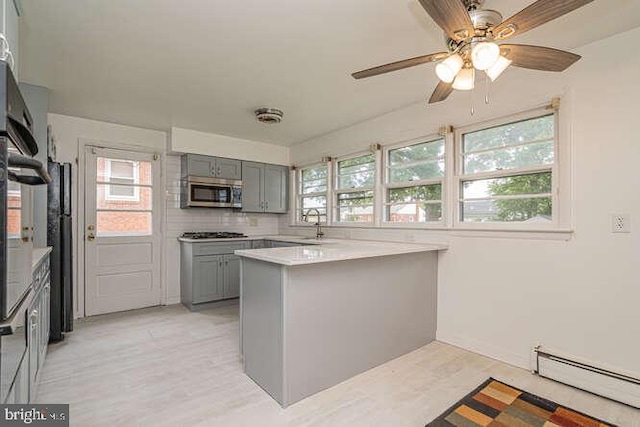 1916 Porter Ave, Suitland, MD 20746 - kitchen featuring stainless steel appliances, gray cabinetry, baseboard heating, a peninsula, and healthy amount of natural light