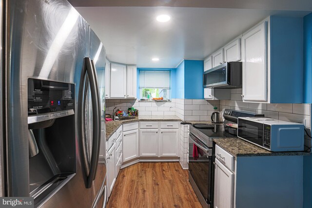 8935 Twin Ridge Dr, Glen Burnie, MD 21061 - kitchen with stainless steel appliances, wood finished floors, white cabinets, backsplash, and dark stone counters